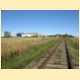 Pohled na horizont trati se zemedělským areálem a vlečkou u bývalé zastávky Dobronín-zastávka.